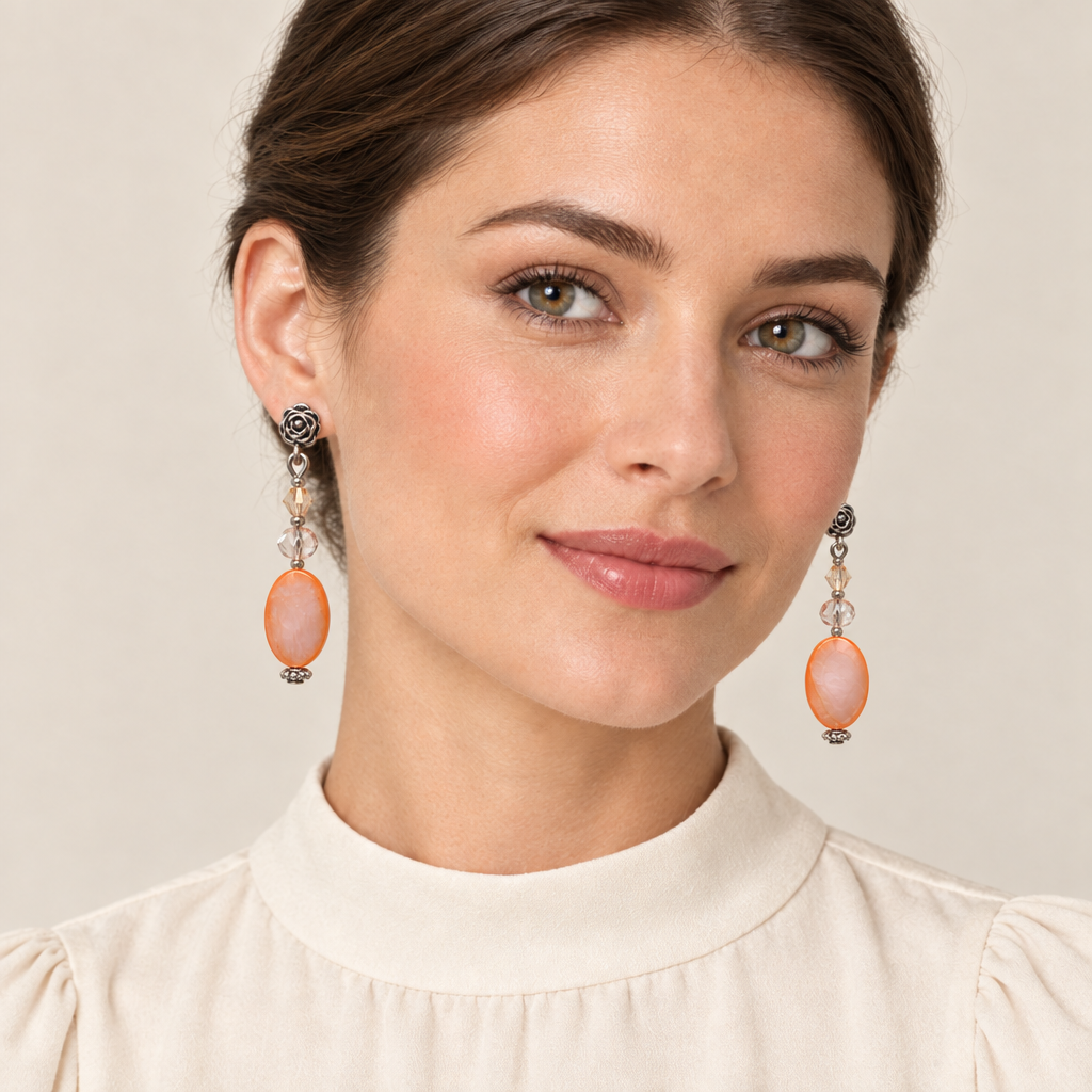 Woman wearing peach shell earrings with two pale crystals